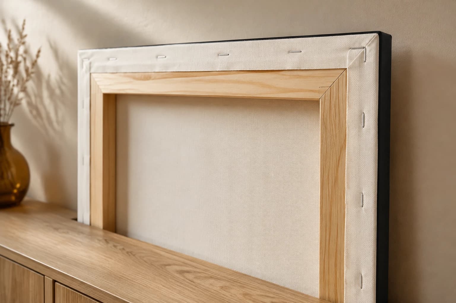 Natural wooden stretcher bars and neatly folded canvas edges in a softly lit interior